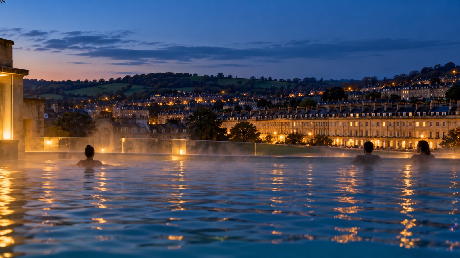 Steam rising from an open-air rooftop pool at twilight, with honey-coloured Georgian terraces and green hills beyond